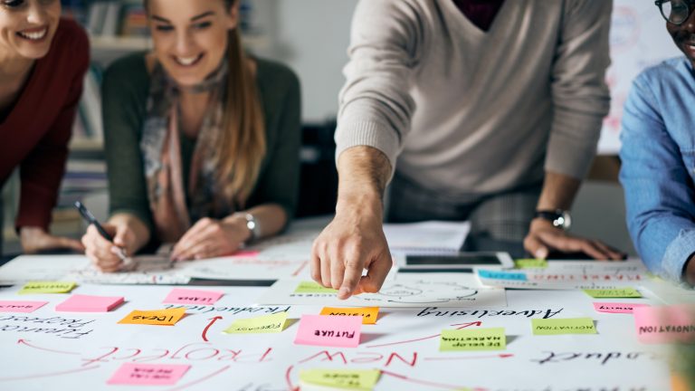 Marketing team using sticky notes on a whiteboard to map the customer journey and customer touchpoints.