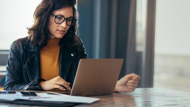Woman working on a laptop reviewing email marketing campaigns at her desk.